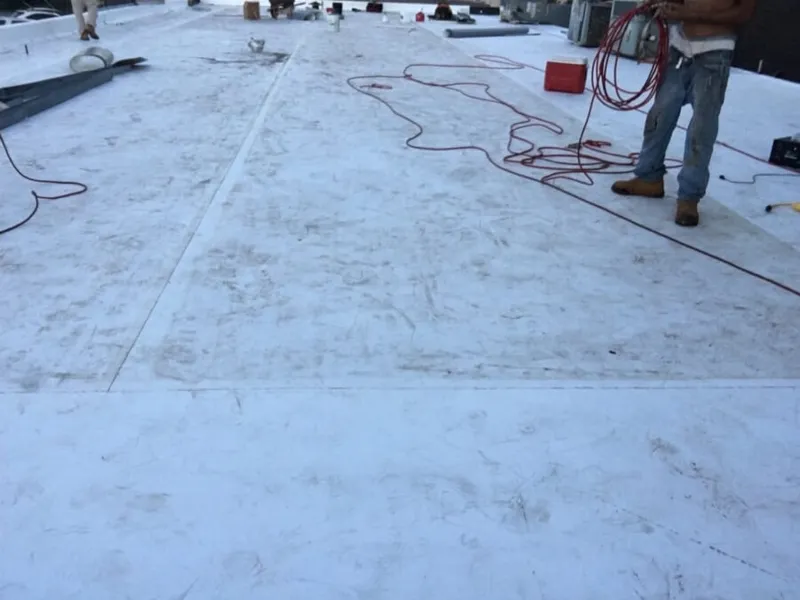 Applying TPO detail membrane up the side of a concrete parapet wall structure